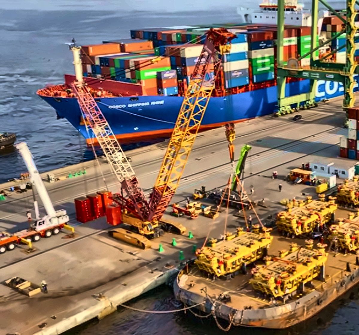 Guindastes treliçados em operação portuária junto a navio cargueiro